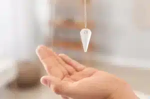 pendule divinatoire tenu à la verticale au dessus d'une main