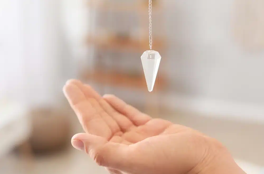 pendule divinatoire tenu à la verticale au dessus d'une main