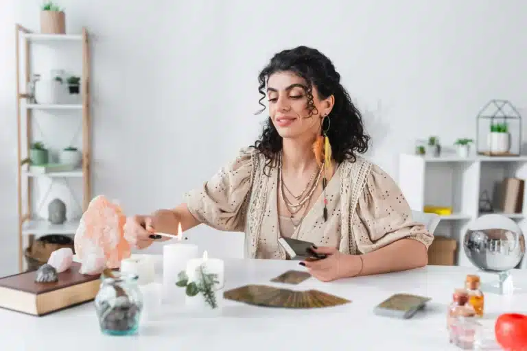 femme qui allume une bougie avec des cartes de tarot sur la table