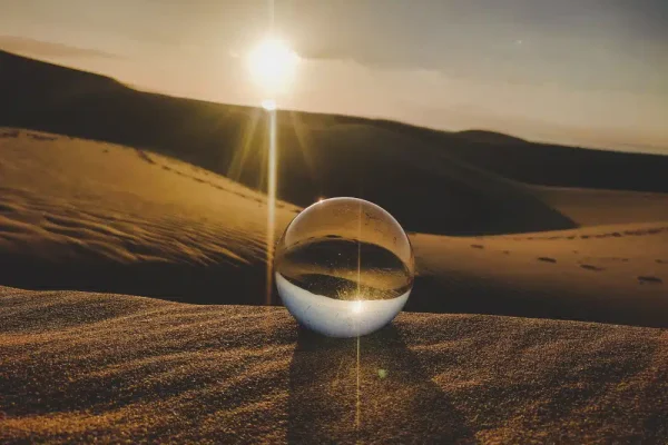boule de cristal sur du sable en plein soleil, symbolise la cristallomancie