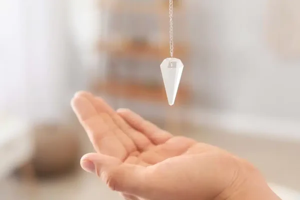 pendule divinatoire tenu à la verticale au dessus d'une main